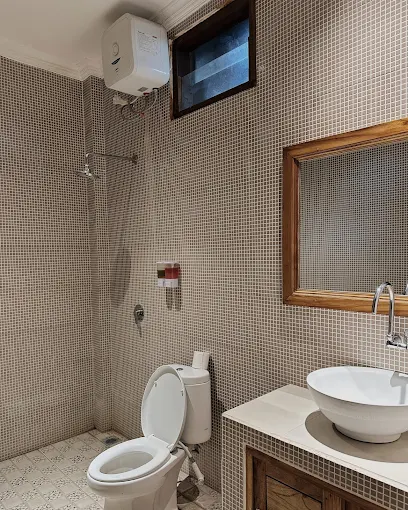 Clean tiled bathroom with shower and stone basin at Divers Cafe Amed