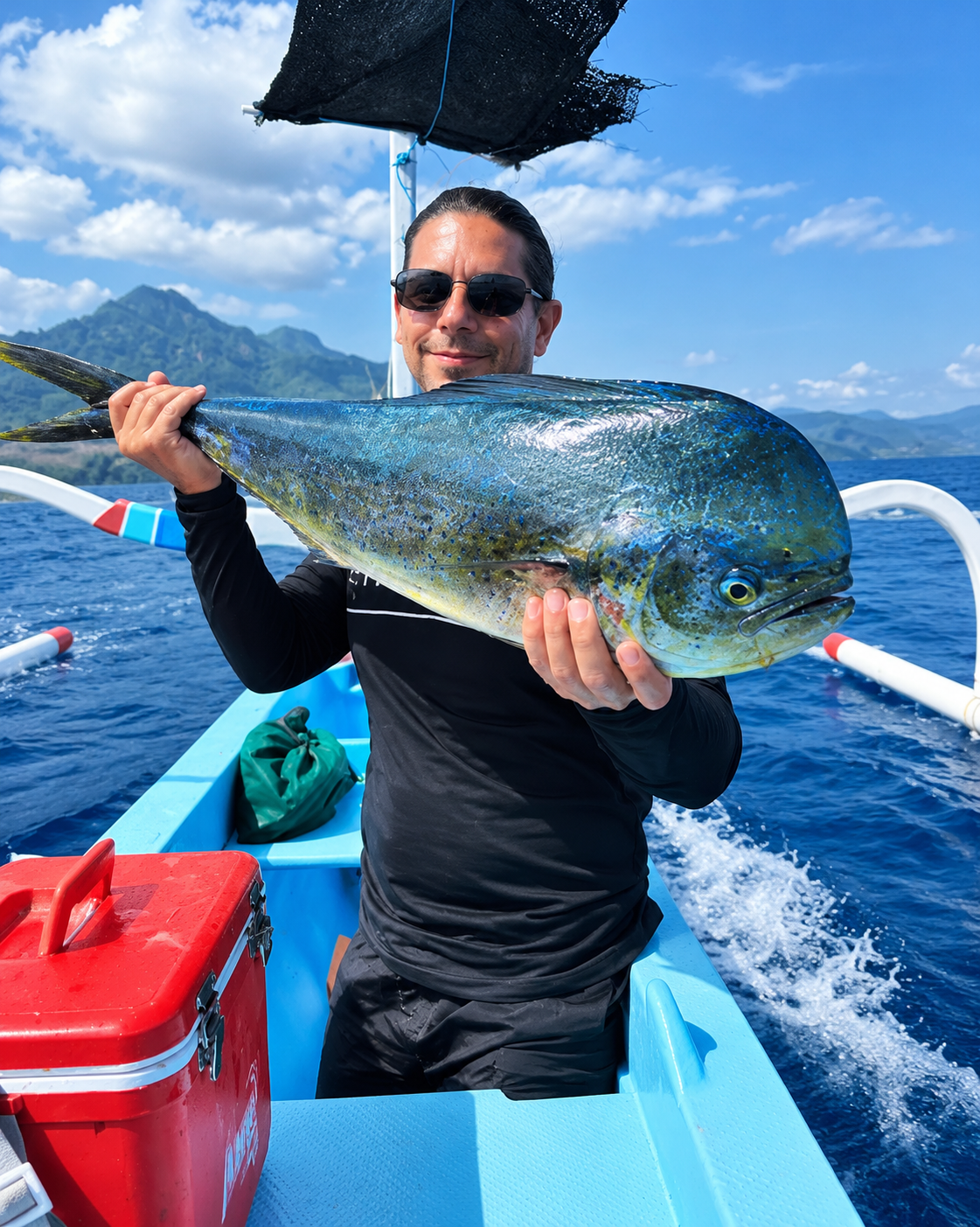 Local fishing guest holding a mahi-mahi caught off Amed at sunrise